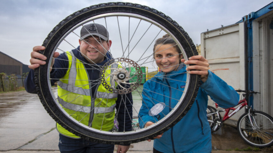 Bryson Recycling are starting to collect bikes at their Ruthin site for local social enterprise Drosi Bikes . Pictured Gerwyn Williams Site Manager at Bryson Recycling site Ruthin with Beth Ward Co-founder Drosi Bikes. Picture Mandy Jones